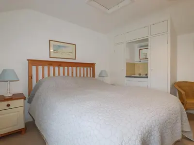 a bedroom with a white bed and a chair at Trewillig Cottage in Wadebridge