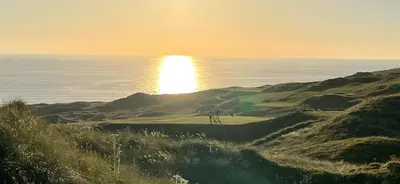 a golf course on a hill with the ocean in the background at Perranporth Golf Club Self-Catering Holiday Accommodation in Perranporth