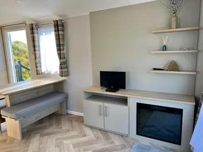a living room with a tv and a desk with a tv at Perranporth Golf Club Self-Catering Holiday Accommodation in Perranporth