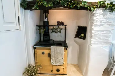 a kitchen with a stove and a table with a towel at Boscastle Quaint Cornish Fishermans Cottage in Boscastle