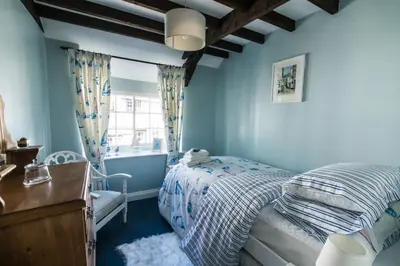 a blue bedroom with a bed and a window at Boscastle Quaint Cornish Fishermans Cottage in Boscastle