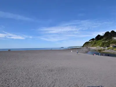 a beach with people walking on the sand at 2 Bed in Torpoint oc-75402 in Downderry