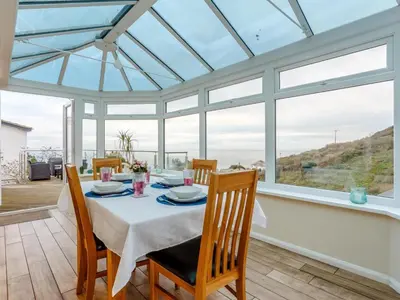 a dining room with a table and chairs and windows at 2 Bed in Torpoint oc-75402 in Downderry