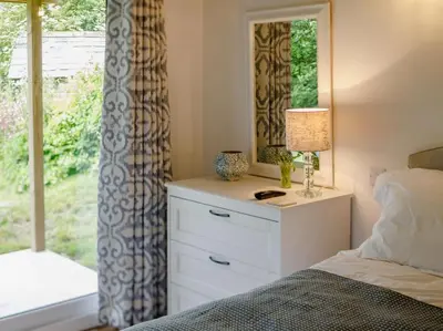 a bedroom with a bed with a dresser and a window at 1 Bed in Looe oc-88434 in Lanreath