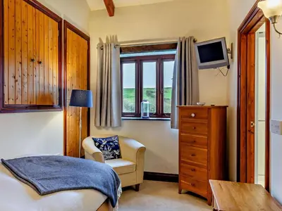 a bedroom with a bed and a chair and a window at 4 Bed in Boscastle oc-47035 in Boscastle