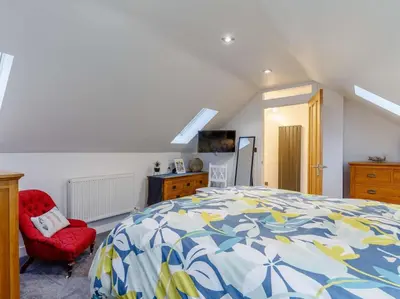 a bedroom with a bed and a red chair at 2 Bed in Redruth oc-86269 in Gwennap