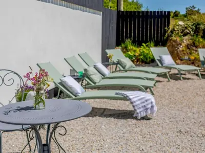 a row of green lounge chairs and tables on a patio at 3 Bed in Redruth oc-88102 in Redruth
