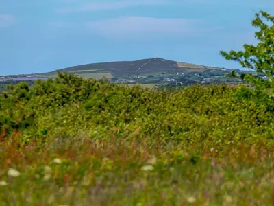 a grassy hill with a mountain in the background at 3 Bed in Redruth oc-88102 in Redruth