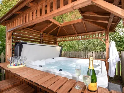 a hot tub in a gazebo with wine glasses at 2 Bed in Truro oc-ljasm in Saint Allen