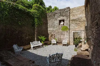 a stone building with two chairs and a window at Catchfrench Manor in Sheviock