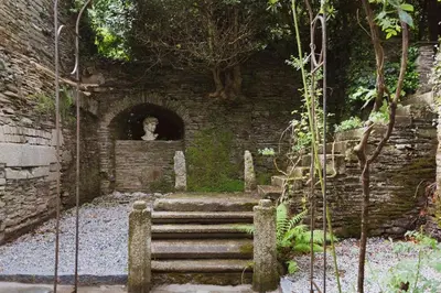 a stone stairway with a statue in a brick wall at Catchfrench Manor in Sheviock