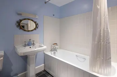 a bathroom with a bath tub and a sink at Catchfrench Manor in Sheviock