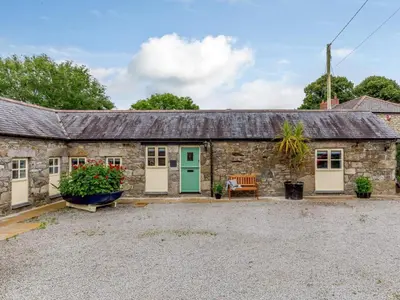 an old stone cottage with a green door and a bench at 2 Bed in Penryn oc-78620 in Penryn