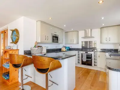 a kitchen with white cabinets and wooden floors at 2 Bed in Redruth oc-sanap in Portreath
