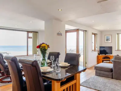 a dining room with a table and a view of the ocean at 2 Bed in Redruth oc-sanap in Portreath