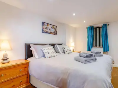 a bedroom with a large white bed with blue curtains at 2 Bed in Redruth oc-sanap in Portreath