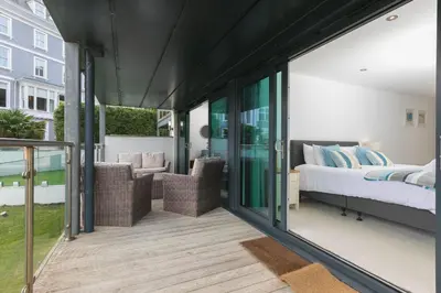 a room with a balcony with a bed and chairs at Number One Peninsula in St Ives