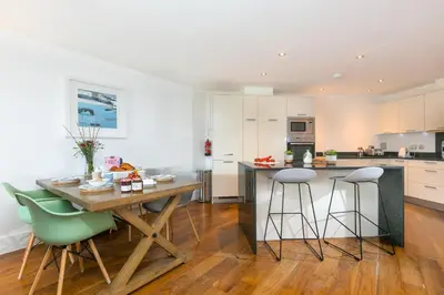 a kitchen with a wooden table and green chairs at Number One Peninsula in St Ives