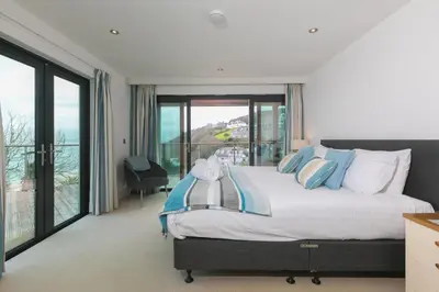 a bedroom with a large bed and a balcony at Number One Peninsula in St Ives