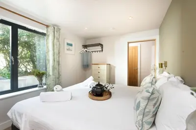 a bedroom with a white bed with a window at Beachside in Newquay
