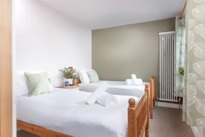 two beds in a room with white walls at Beachside in Newquay