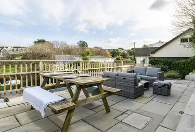 a patio with a wooden table and chairs on a deck at Beachside in Newquay