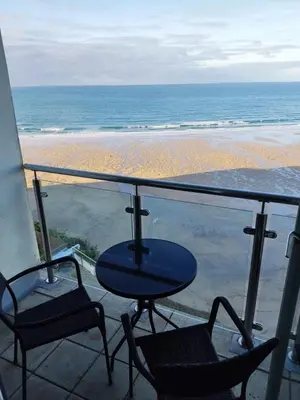 a balcony with a table and chairs and the beach at Newquay Rocklands Beach View in Newquay