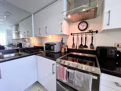 a kitchen with a stove and a clock on the wall at Newquay Rocklands Beach View in Newquay