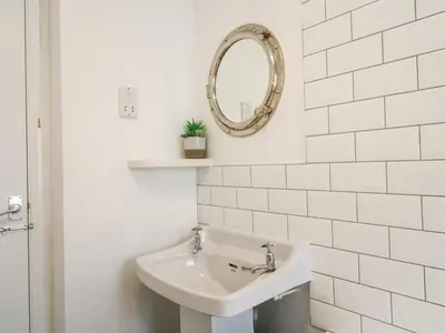 a white bathroom with a sink and a mirror at Kelsey in Truro