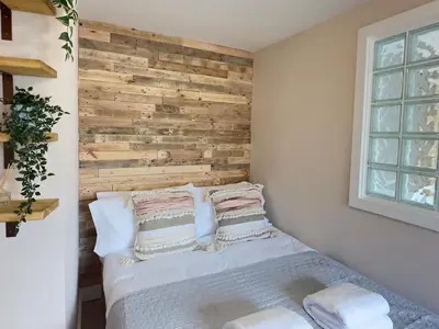 a bedroom with a wooden accent wall and a bed at Aggie Beach Apartment - Unrivalled Beach Views in St. Agnes