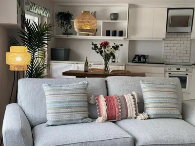 a living room with a gray couch with pillows at Aggie Beach Apartment - Unrivalled Beach Views in St. Agnes