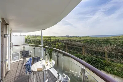 a balcony with a table and chairs and the ocean at 10 Bredon Court - Close to Town & Beaches - Free Parking & WiFi - Sea View in Newquay