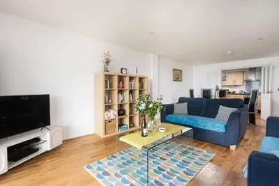 a living room with a blue couch and a tv at 10 Bredon Court - Close to Town & Beaches - Free Parking & WiFi - Sea View in Newquay