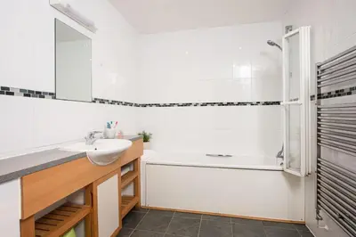 a white bathroom with a sink and a tub and a mirror at 10 Bredon Court - Close to Town & Beaches - Free Parking & WiFi - Sea View in Newquay