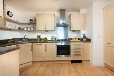 a kitchen with wooden cabinets and stainless steel appliances at 10 Bredon Court - Close to Town & Beaches - Free Parking & WiFi - Sea View in Newquay