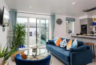 a living room with a blue couch and a glass table at 1 Cliff Edge in Newquay in Newquay