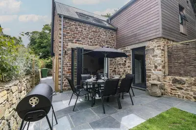 a patio with a table and chairs and an umbrella at Wildwood in Newquay