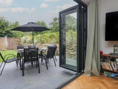 a patio with a table and chairs and an umbrella at Wildwood in Newquay