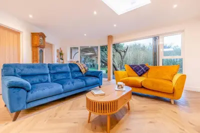 a living room with a blue couch and yellow chairs at Luxury holiday home near the coast in Porthtowan