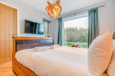 a bedroom with a large bed with a large window at Luxury holiday home near the coast in Porthtowan