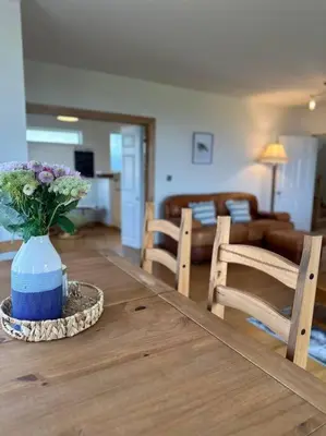 a vase of flowers sitting on a wooden table at The Surf House (Widemouth Bay) in Bude