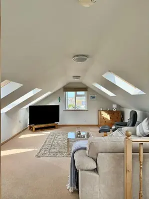 a living room with a couch and a flat screen tv at The Surf House (Widemouth Bay) in Bude