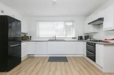 a kitchen with white cabinets and a black refrigerator at Ocean Aura in Carbis Bay