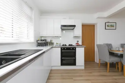 a kitchen with white cabinets and a dining table at Ocean Aura in Carbis Bay