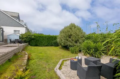 a backyard with a lawn with chairs and plants at Ocean Aura in Carbis Bay