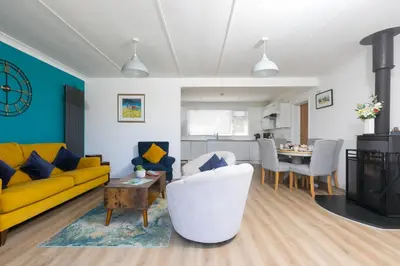 a living room with a yellow couch and a table at Ocean Aura in Carbis Bay