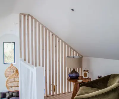 a room with a staircase with a chair and a lamp at Lowen Tree House in Truro