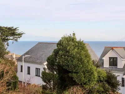 a white house with the ocean in the background at Ocean View in St Ives