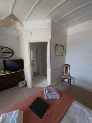 a bedroom with a bed and a television and a chair at The Fieldings in Truro