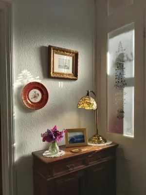 a room with a table with a lamp and pictures on the wall at The Fieldings in Truro